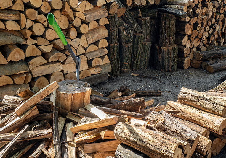 A pile of logs with a green tool positioned in the center, surrounded by natural wood textures.